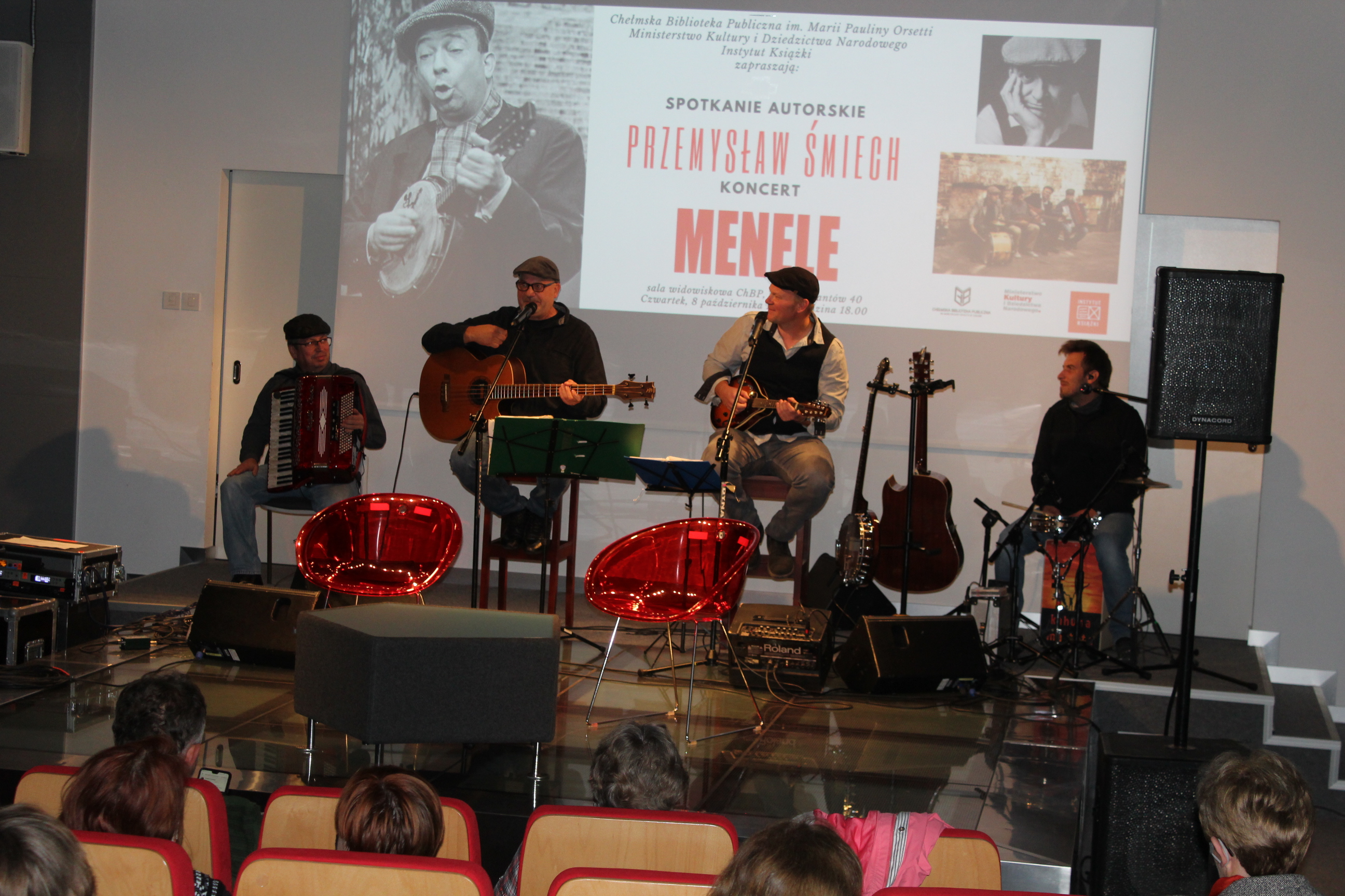 Członkowie zespołu Menele, czterech mężczyzn, na scenie z instrumentami.