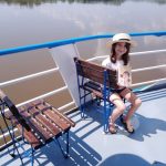 Dziewczynka siedzi na ławce na statku. W tle jezioro.