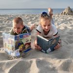 Chłopiec i dziewczynka czytają książkę w na plaży.