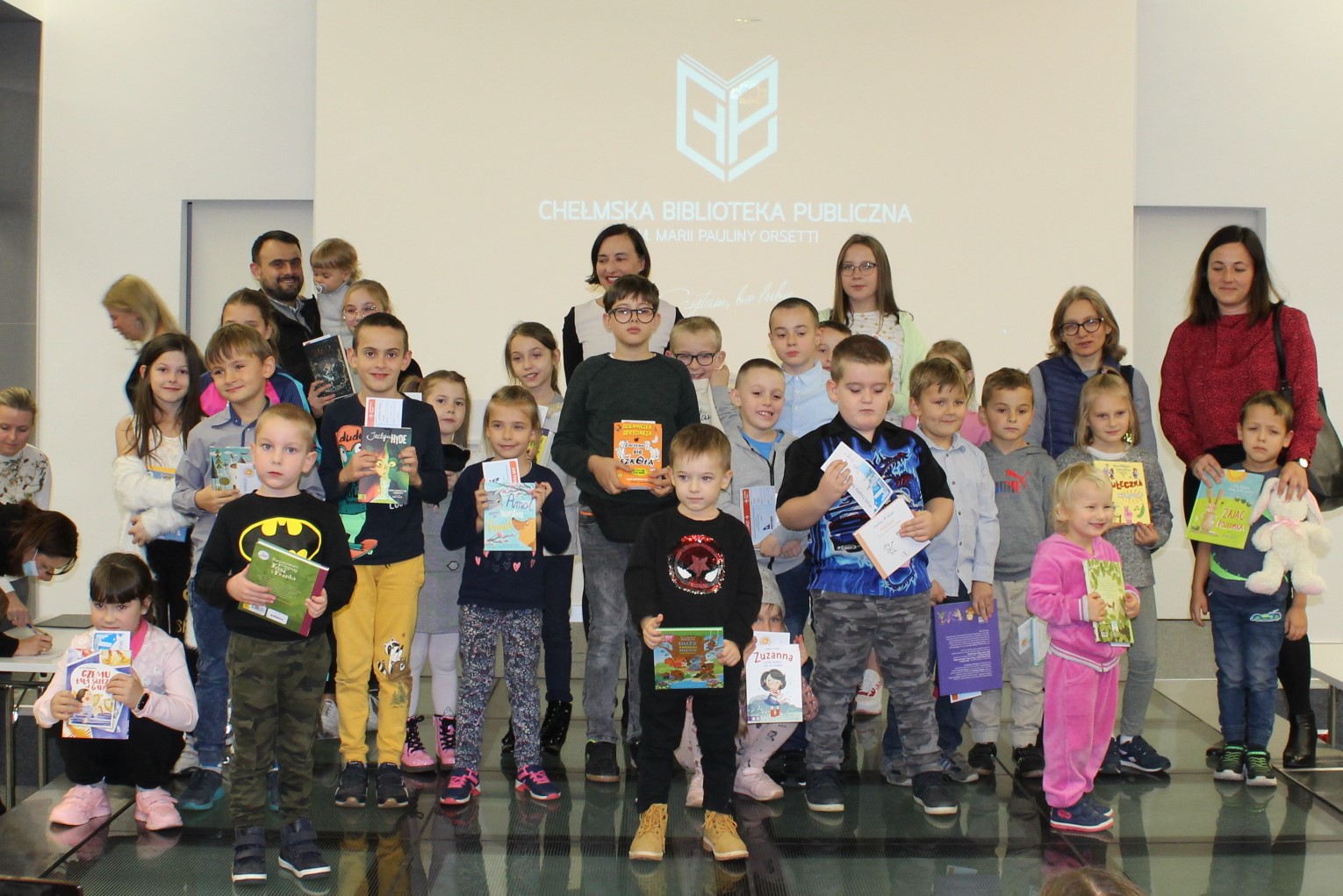 Laureaci konkursu Wyślij książkę na wakacje. stoją na scenie w sali widowiskowej Chełmskiej Biblioteki Publicznej.