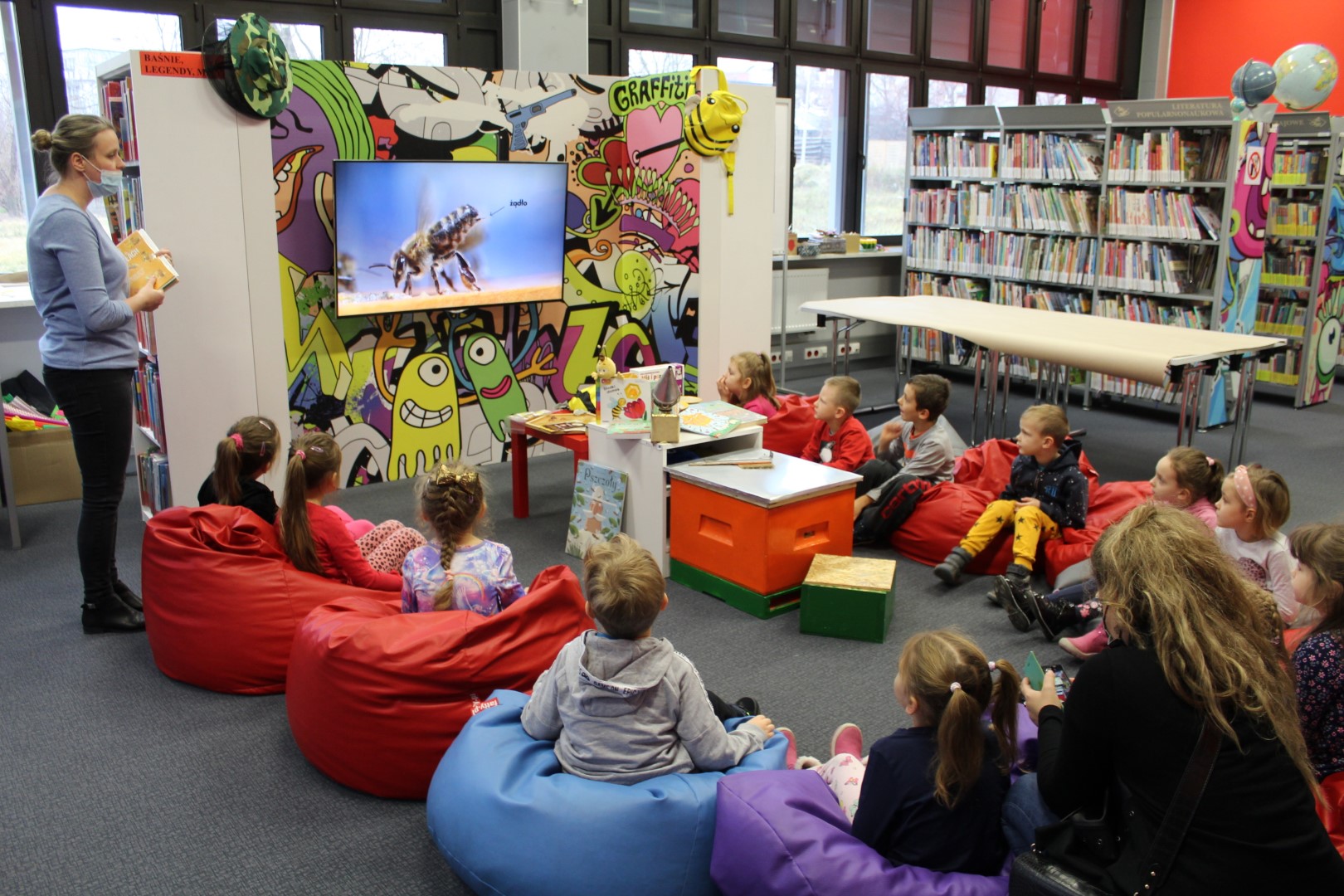 Grupa dzieci podczas warsztatów o pszczołach ogląda film edukacyjny.