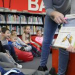 Bibliotekarka pokazująca dzieciom książkę o pszczołach.