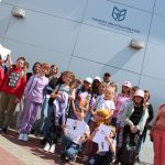 Grupa dzieci pozuje przed budynkiem ChBP w letni słoneczny dzień