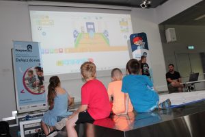 Dzieci patrzą na ekran, na którym wyświetlany jest program edukacyjny Scratch Junior.