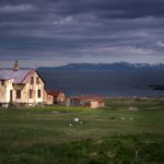 Islandia: opuszczone domostwo nad morzem, w tle góry. Niebo zachmurzone