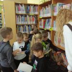 Pomieszczenie biblioteki: grupa dzieci przegląda książki