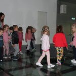 Grupa dzieci w wieku przedszkolnym stoi na scenie w sali widowiskowej