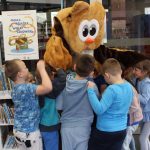 W pomieszczeniu Wypożyczalni dla dzieci, dzieci przytulają się do pluszowej sowy - pracownika biblioteki w przebraniu