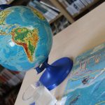 Globus, książka i szklanka z przezroczystym płynem