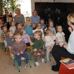 Grupa dzieci słucha czytającej bibliotekarki