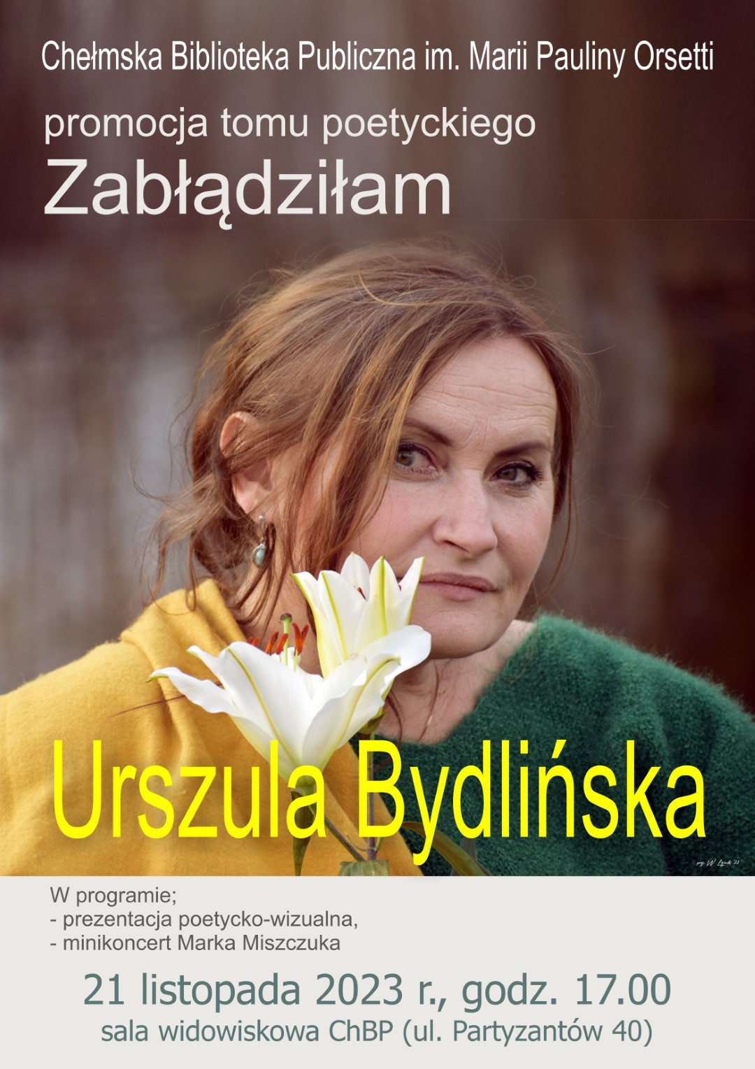 Plakat promujący promocję tomiku poetyckiego Urszuli Bydlińskiej pt Zbłądziłam. Na plakacie autorka - kobieta o brązowych włosach trzymająca kwiat lilii, ubrana żółta bluzę i zielony sweter