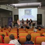 Autorzy książki - kobiet i mężczyzna oraz prowadząca spotkanie na scenie sali widowiskowej biblioteki