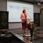 Na scenie w sali widowiskowej przemawiająca kobieta