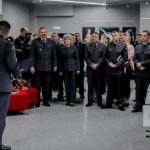 Liczna grupa mundurowych pozuje do zdjęcia, przed nimi na pierwszym planie przemawia mundurowy