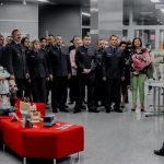 Liczna grupa mundurowych pozuje do zdjęcia, wśród nich kobieta z bukietem kwiatów