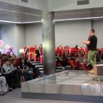 Na scenie przemawiający mężczyzna Franciszek Piątkowski Publiczność podczas spotkania siedzą na czerwonych fotelach patrzą na scenę