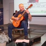 Mężczyzna grający na gitarze podczas uroczystości z okazji 80-lecia urodzin Zbigniewa Waldemara Okonia
