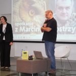Marcin Kostrzyński wraz z zapowiadającą kobietą przemawia w tle plakat ze zwierzętami