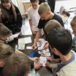 Młodzież, uczestnicy Narodowego Czytania gromadzą się wokół stołu na którym leżą zakładki