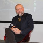 Na scenie sali widowiskowej mężczyzna patrzy przed siebie