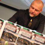 Na pierwszym planie książki na drugim mężczyzna który patrzy w dół