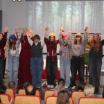 Na scenie sali widowiskowej dzieci unoszą ręce do góry