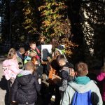 Dzieci patrzą na kobietę , która stoi przy drzewie