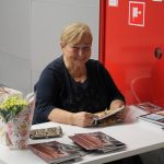Sprzedająca książki kobieta uśmiecha się do aparatu