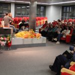 Na scenie sali widowiskowej muzycy oraz poetka, w tle widzowie podczas spotkania