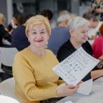 Kobieta pokazująca zapisaną kartkę stalówką maczaną w kałamarzu