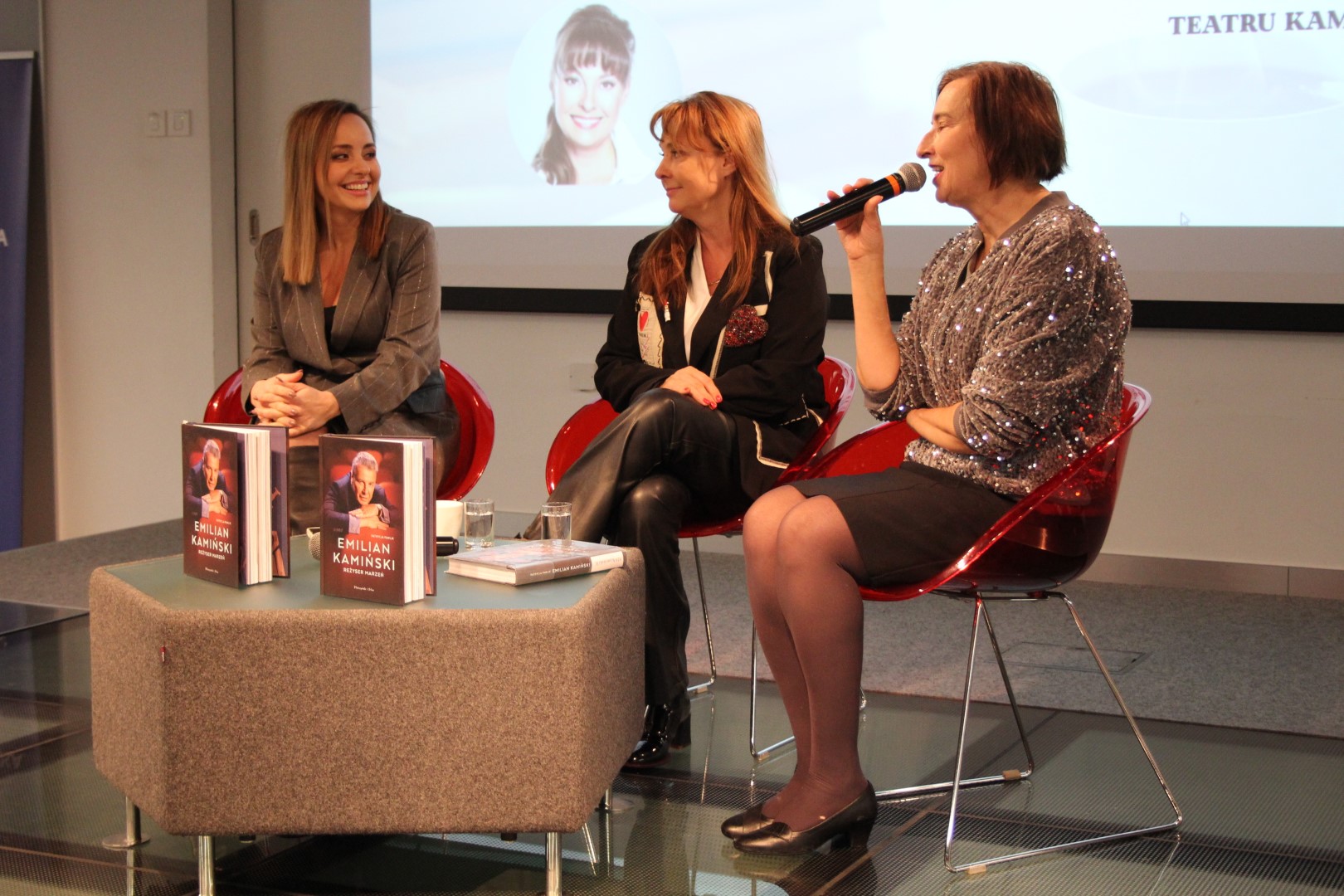 3 Kobiety na scenie sali widowiskowej biblioteki rozmawiają siedząc przy stoliku