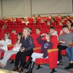 Dzieci siedzą w sali widowiskowej biblioteki