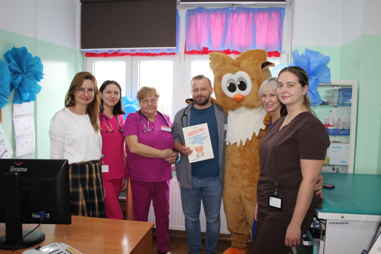 Grupa osób, kobiety - pielęgniarki oraz lekarz, mężczyzna w stroju sowy pozują do zdjęcia