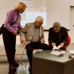 Uczestnicy spotkania z Adamem Kulikiem, który podpisuje autografy.