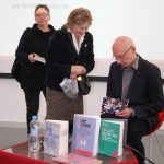 Mężczyzna - zaproszony językoznawca podpisuje książkę czytelniczkom