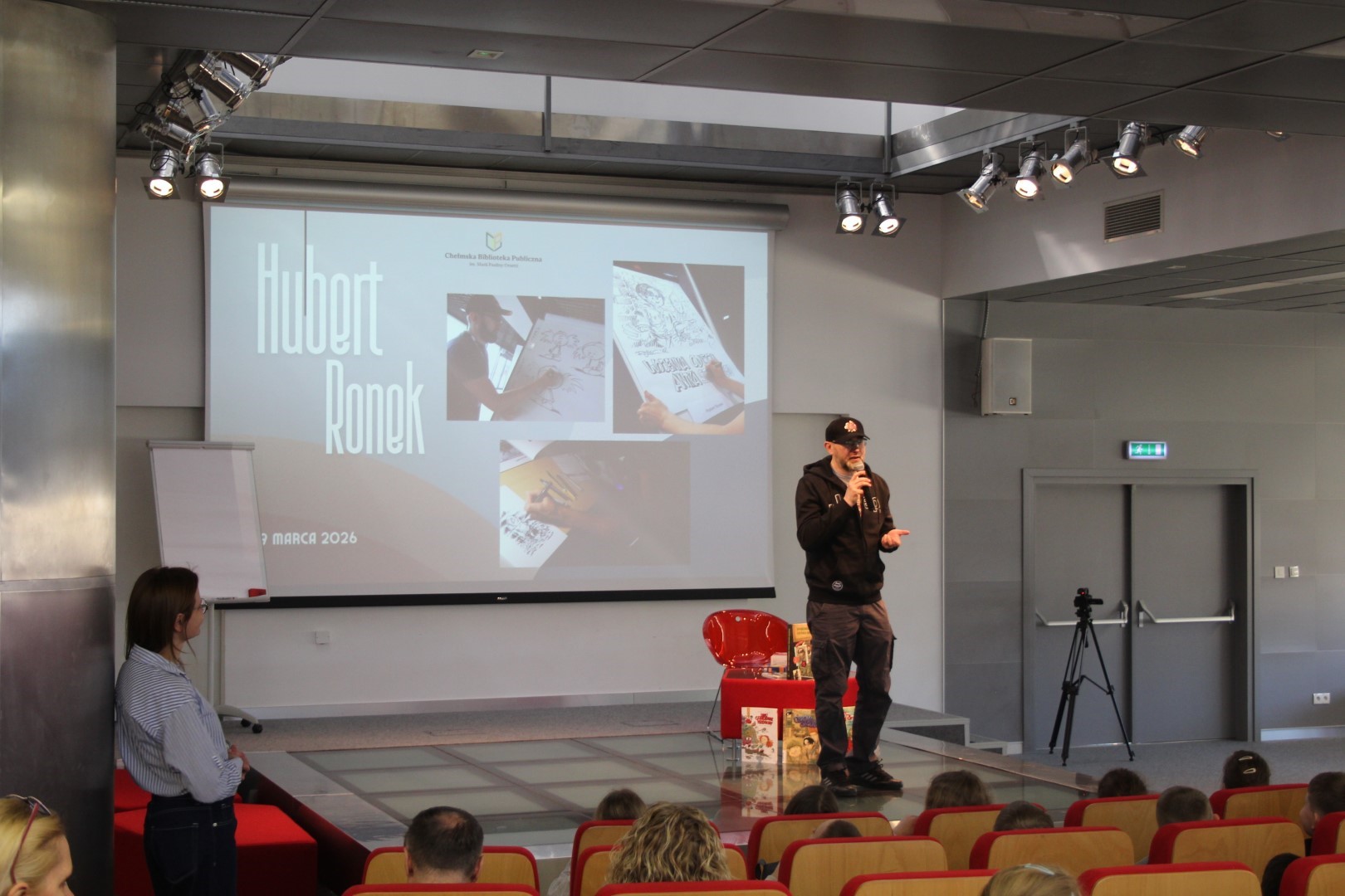 Rysownik - Hubert Ronek na scenie sali widowiskowej biblioteki