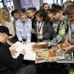 Uczestnicy spotkanie z rysownikiem Hubertem Ronkiem czekają na autograf