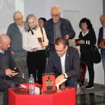 Uczestnicy spotkania z Mirosławem Czechem stoją w kolejce po autograf, autor podpisuje książki